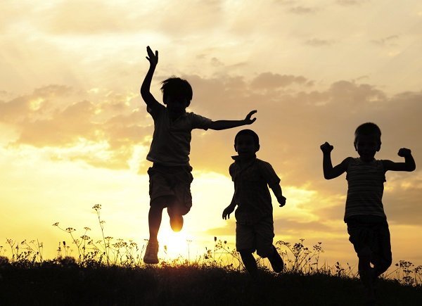 Children running on meadow at sunset