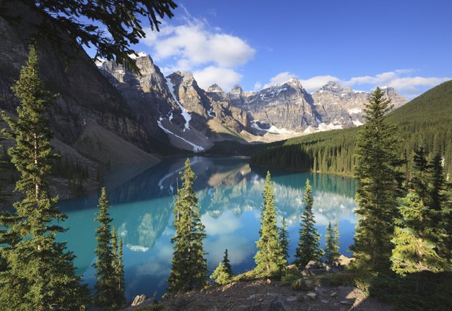 A view of mountains over a lake with trees. Lake Moraine, Banff National Park, Alberta, Canada.